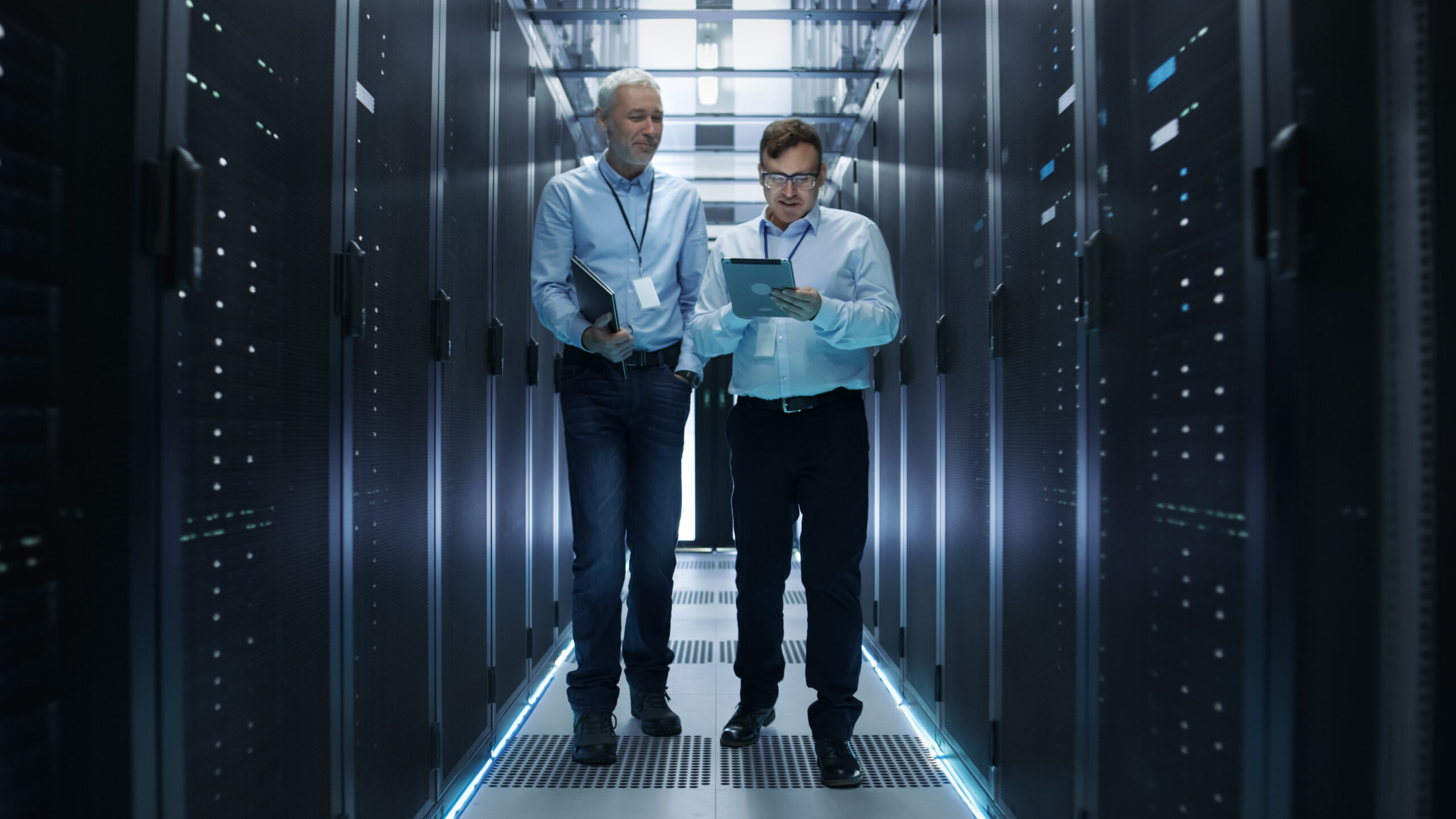 two men talking about IT infrastructure while walking through an IT server room