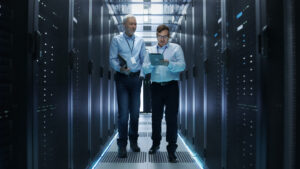 two men talking about IT infrastructure management while walking through an IT server room.
